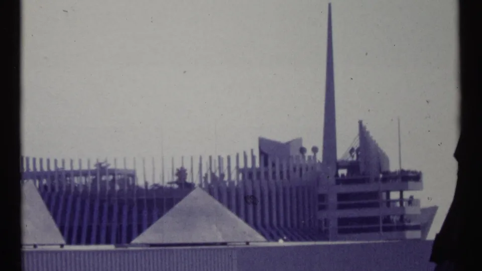 1967 Montreal 8mm view of a modernist building with ribbed wall sections, triangular roof forms, and a slender spire.