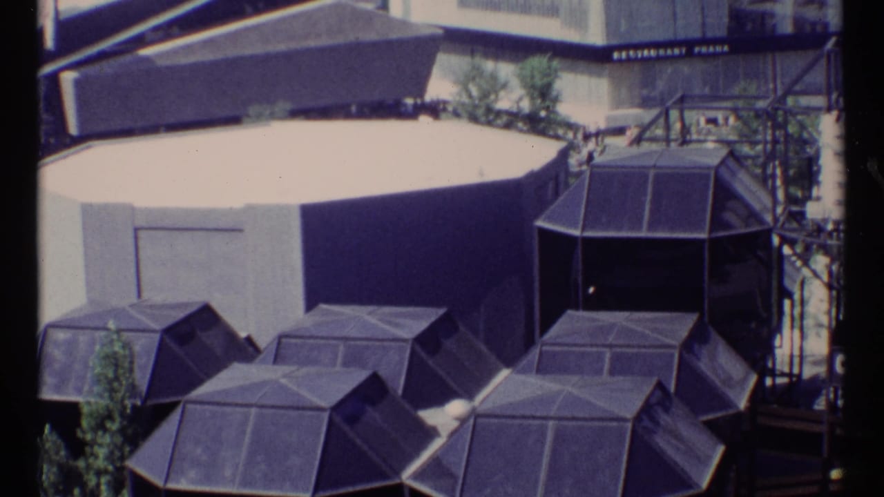 Elevated view of polygonal pavilion roofs and a pale round building at Expo 67.