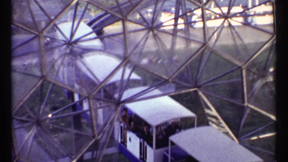 A visitor's elevated view catches the trolley and passengers moving through the glass geodesic dome in Montreal.