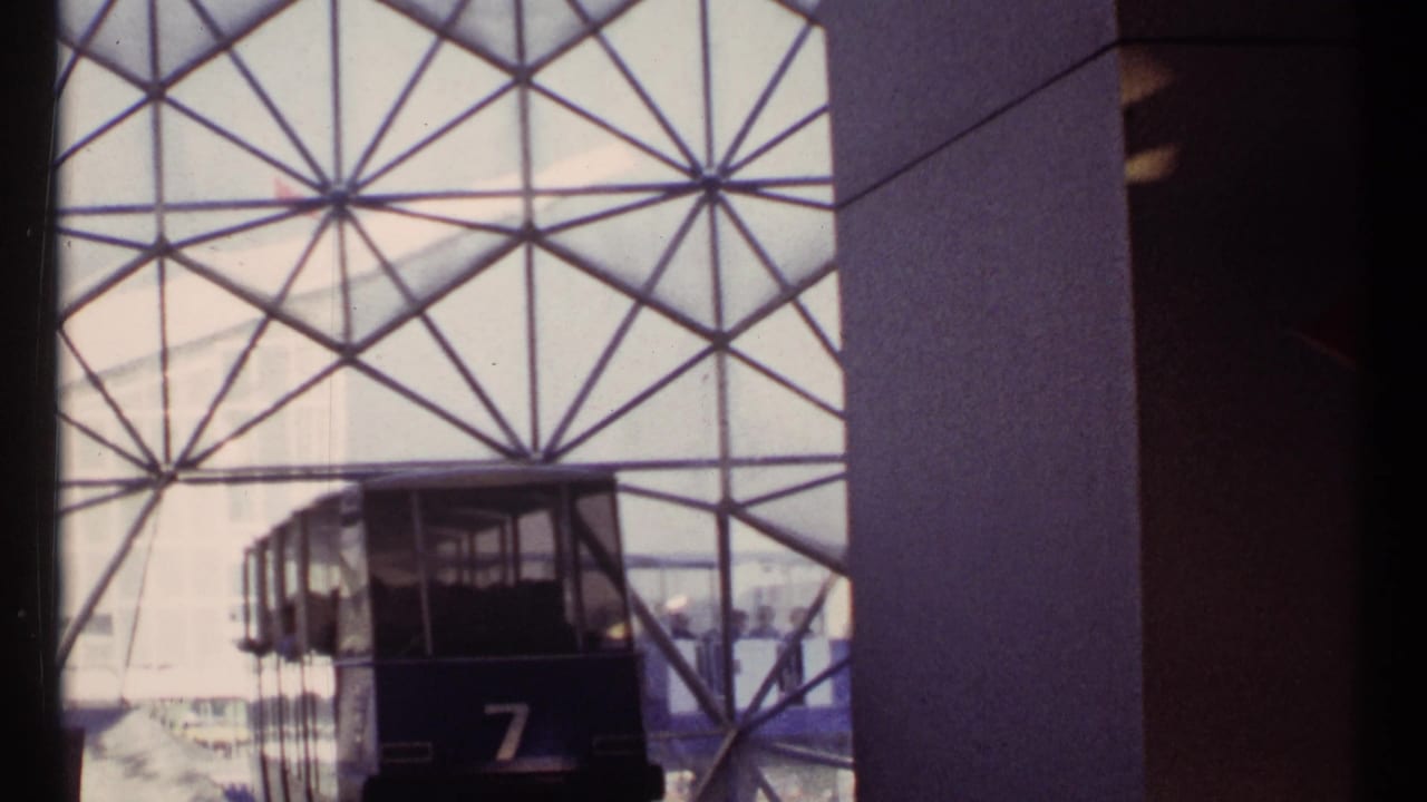 Front of tram 7 moves closer inside the station beside a tall column.