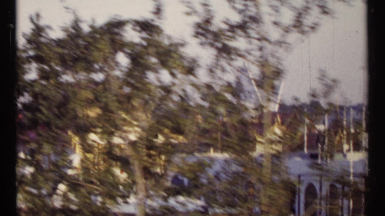 Blurred trees and distant buildings seen from a moving vehicle or train.