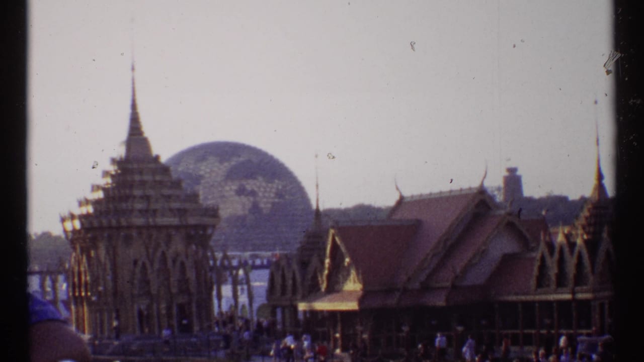 Pavilion roofs and spires beside water with the geodesic dome in the distance.