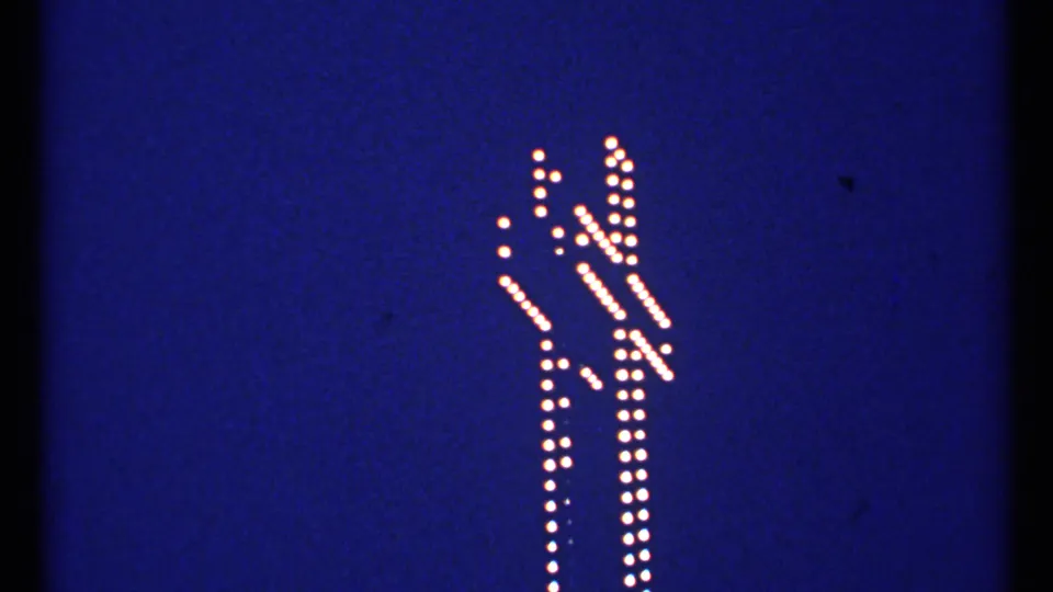 1967 Montreal frame with the illuminated cross outline held steady against a clear blue evening sky.
