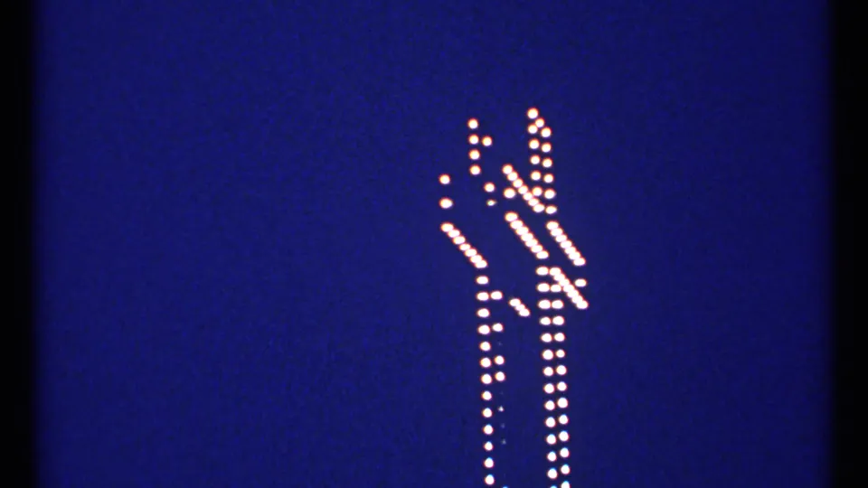 1967 Montreal 8mm still of a dotted white illuminated cross outline with rich blue film color.