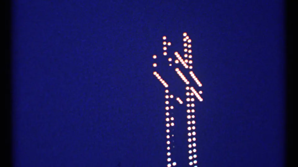 Final 1967 Montreal frame showing the same white bulb-lit cross outline against the blue evening sky.