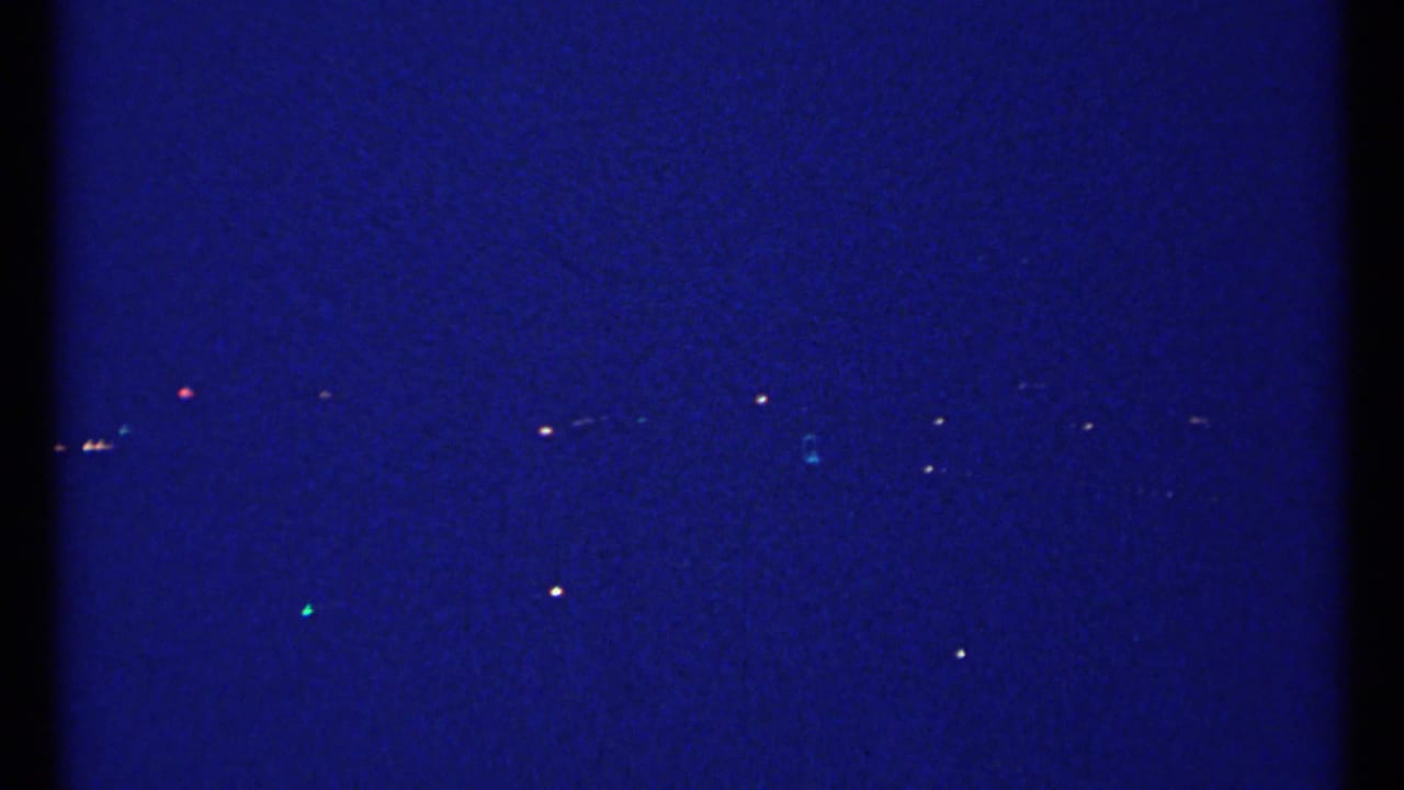 Deep blue night sky with scattered distant city lights near the horizon.