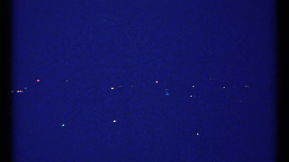 1967 Montreal home-movie frame showing a dark blue night sky with small distant lights across the horizon.