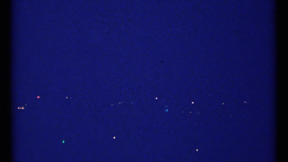 1967 Montreal night view with distant city lights and a faint illuminated cross-like landmark shape in the blue sky.