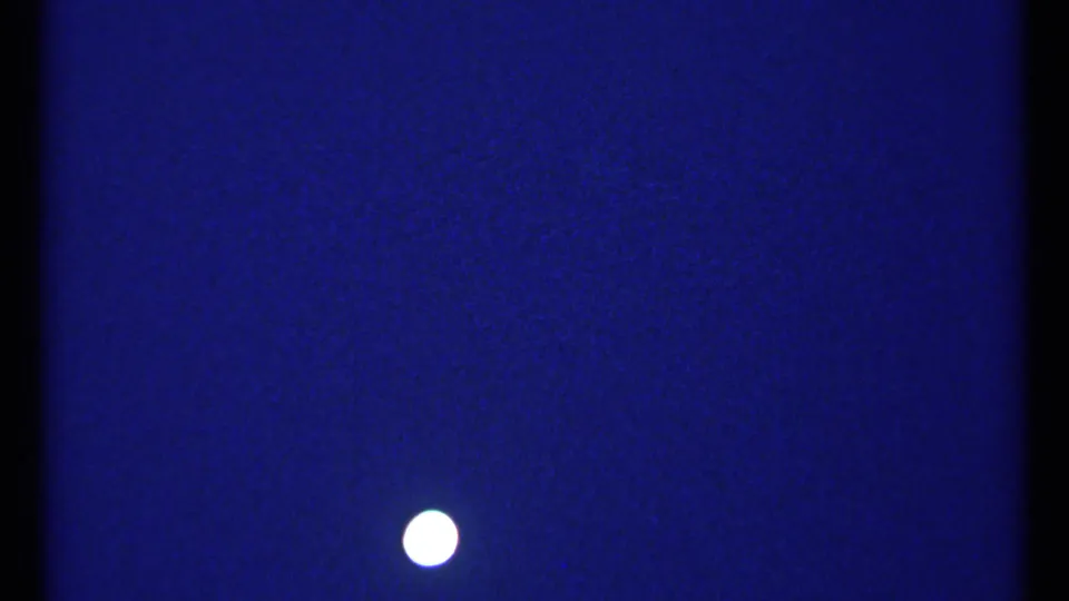 1967 Montreal nighttime frame with a bright moon low in the blue sky and faint city lights in the distance.