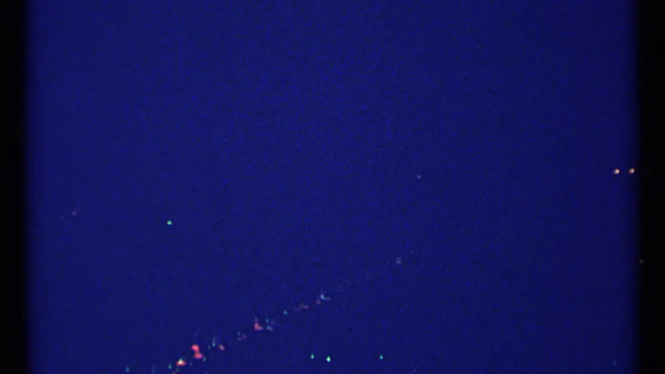 Blue-tinted 8mm frame showing a dark sky or underexposed scene with small scattered lights, likely from the same Montreal travel sequence.