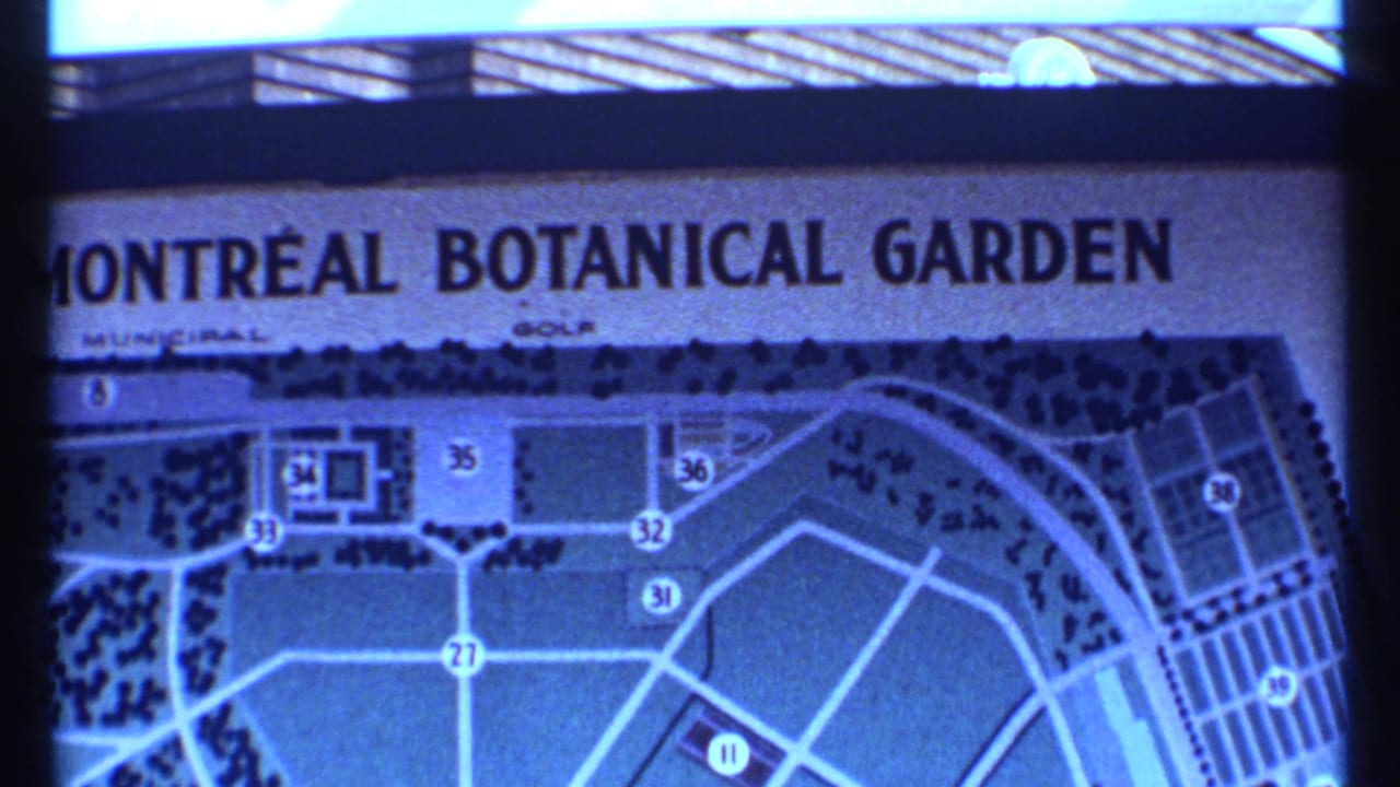 Partial view of the Montreal Botanical Garden sign and site map, with numbered paths visible in blue-tinted 8mm footage.