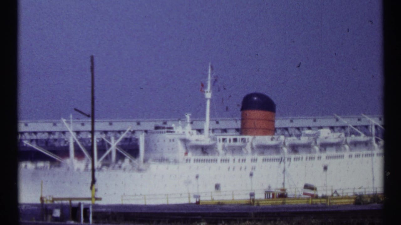 1967 Montreal home-movie frame showing a large white ocean liner at dock, with lifeboats, mast, and a red-and-black smokestack visible.