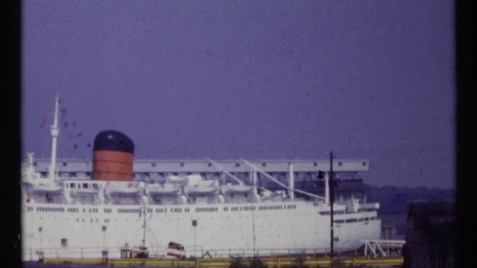 A closer cropped 1967 frame shows the liner's side, rows of windows, lifeboats, red-and-black funnel, and dockside railings.