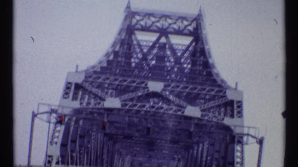 1967 Montreal road view entering the steel truss bridge structure, with traffic signals and bridge framing overhead.