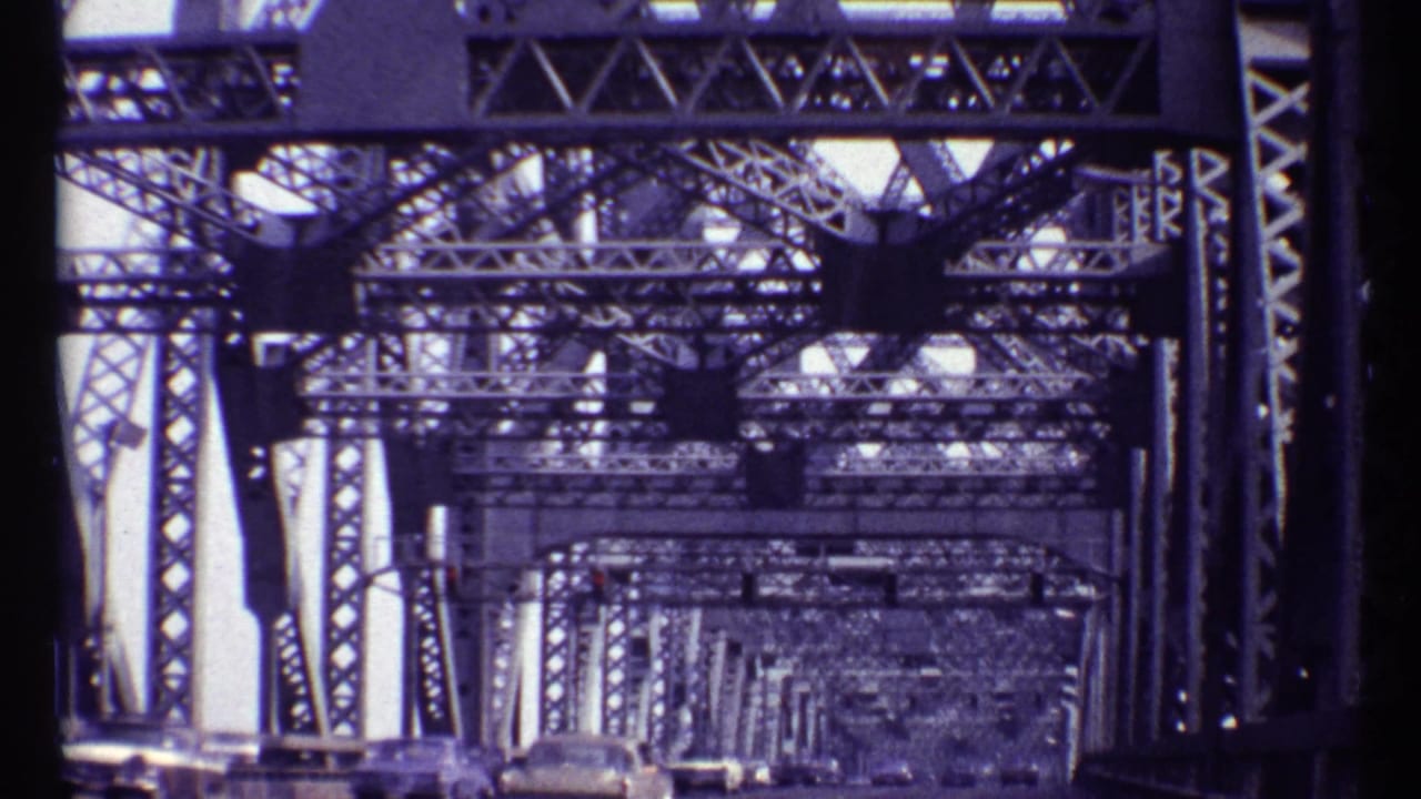 View inside a steel truss bridge with cars ahead on the roadway.