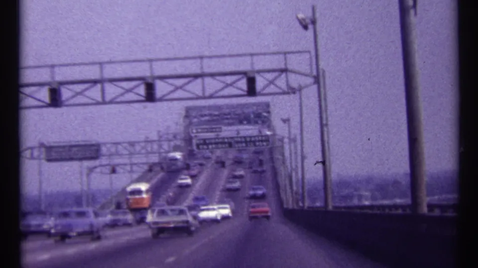 1967 Montreal bridge crossing with cars spread across lanes beneath overhead signs and signal structures.