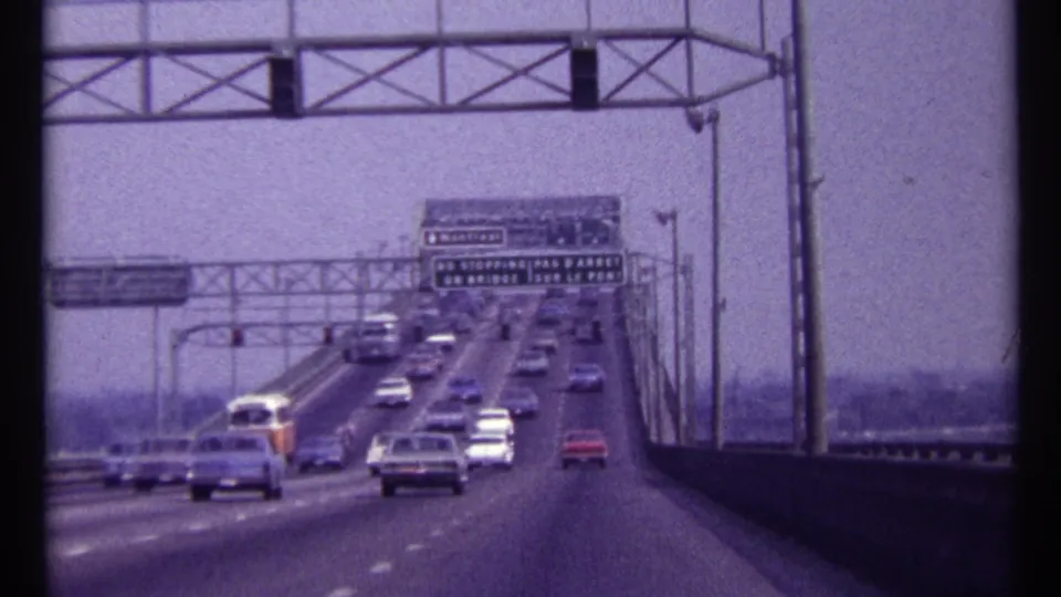 1967 Montreal bridge traffic with classic cars, overhead roadway signs, side railings, and a soft purple 8mm film cast.