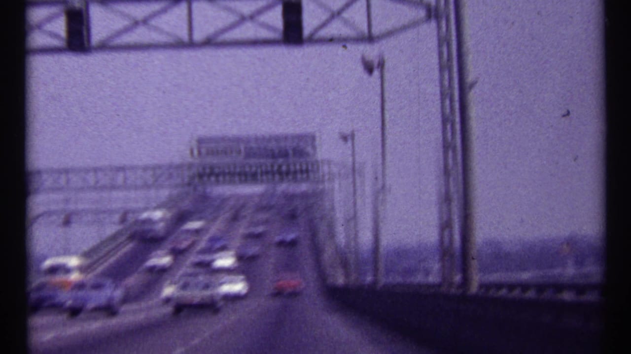 Bridge roadway with moving cars beneath overhead metal gantries.