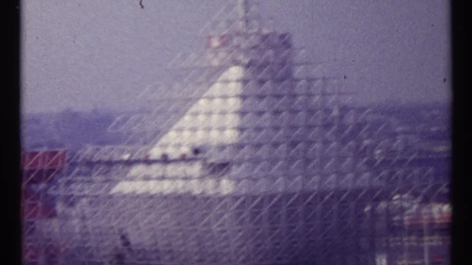 1967 Montreal 8mm frame showing a pale pyramid-like structure wrapped in lattice scaffolding beneath a purple-tinged sky.