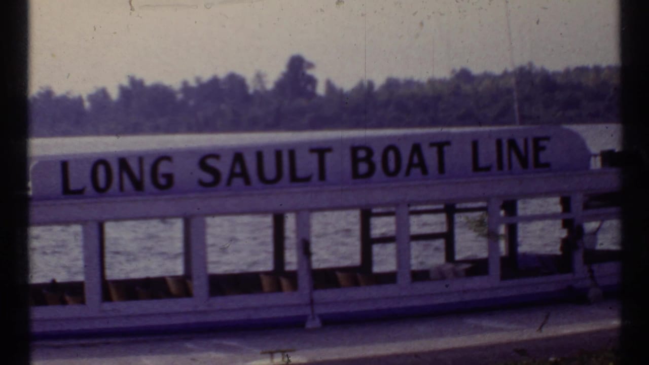 White passenger boat with LONG SAULT BOAT LINE lettering on a river.