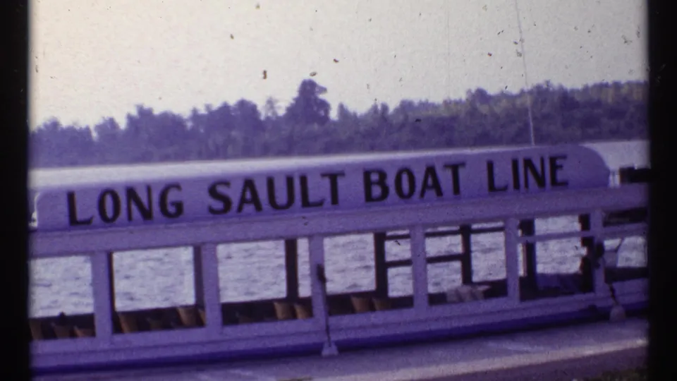 1967 Montreal 8mm frame showing Long Sault Boat Line lettering on a white vessel with water and shoreline behind it.