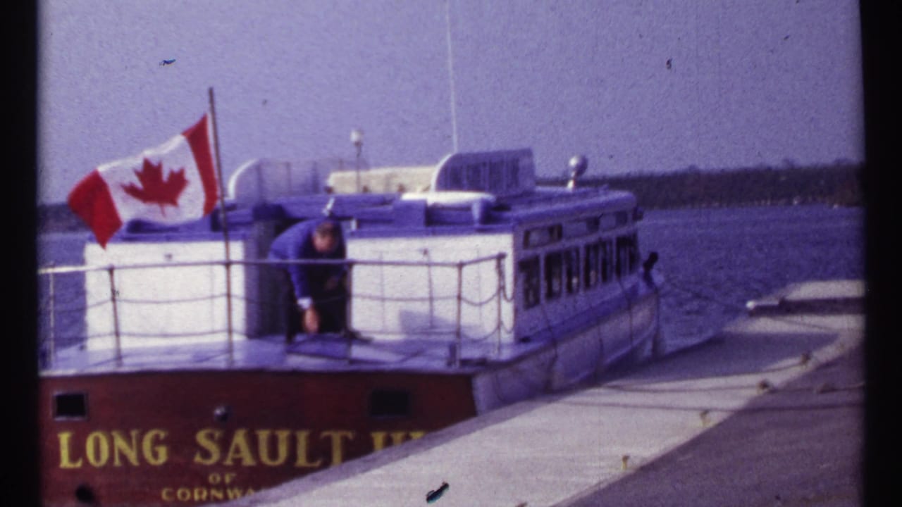 Canadian flag flying on a docked Long Sault boat with a man near the stern.