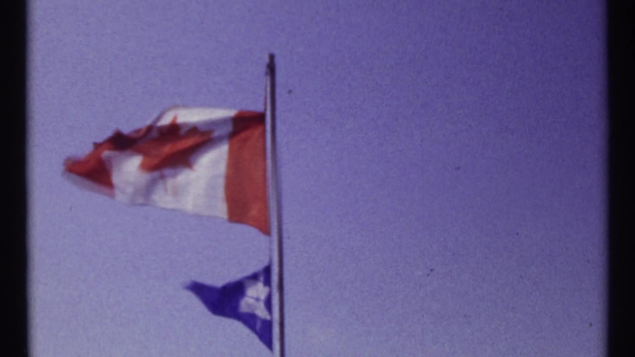 1967 Montreal-linked 8mm frame showing a Canadian flag above a smaller blue Star of David flag in strong wind.