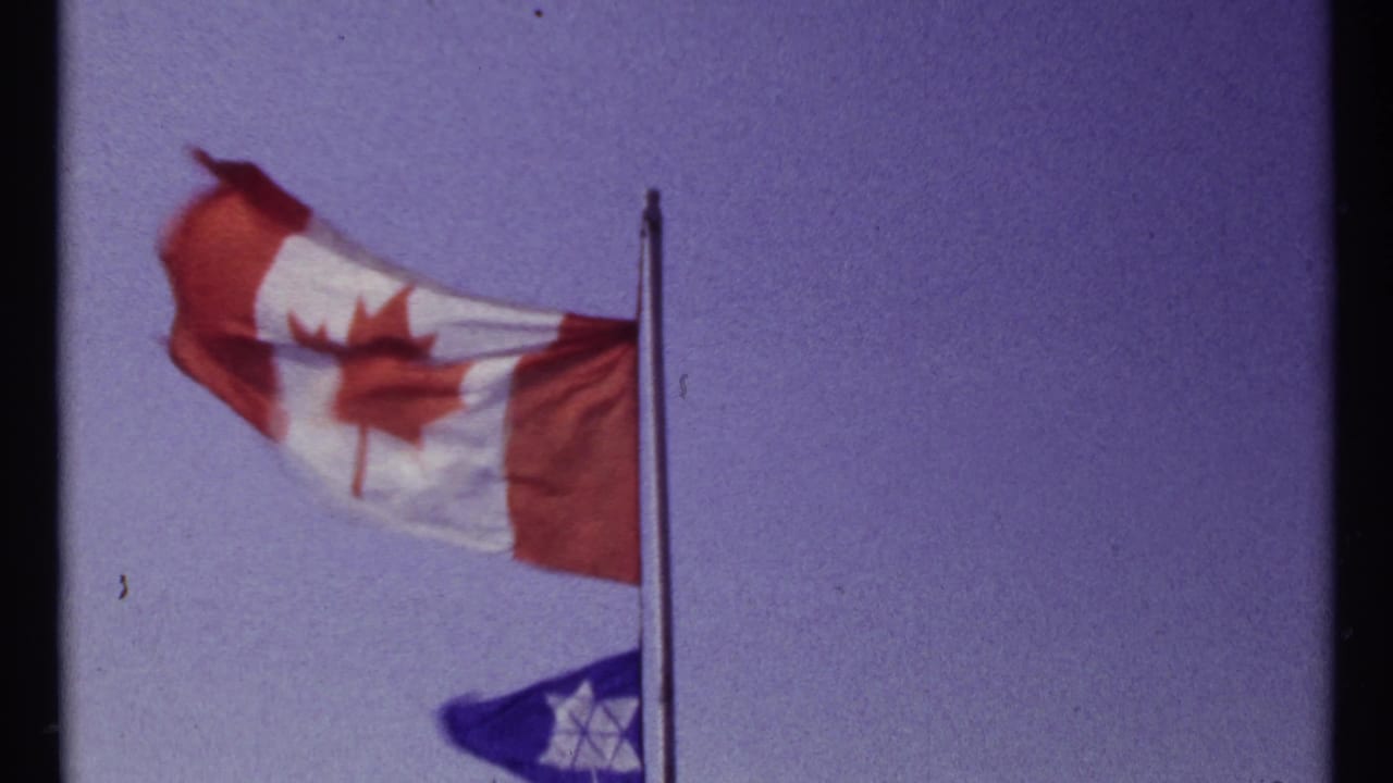 Canadian flag flying above a smaller blue Star of David flag on a pole.