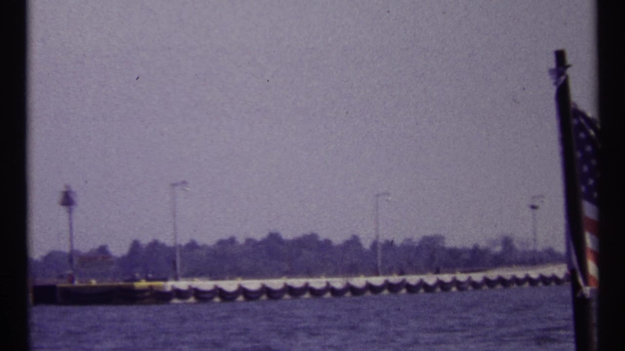 Waterfront pier with lampposts and an American flag at the right edge.