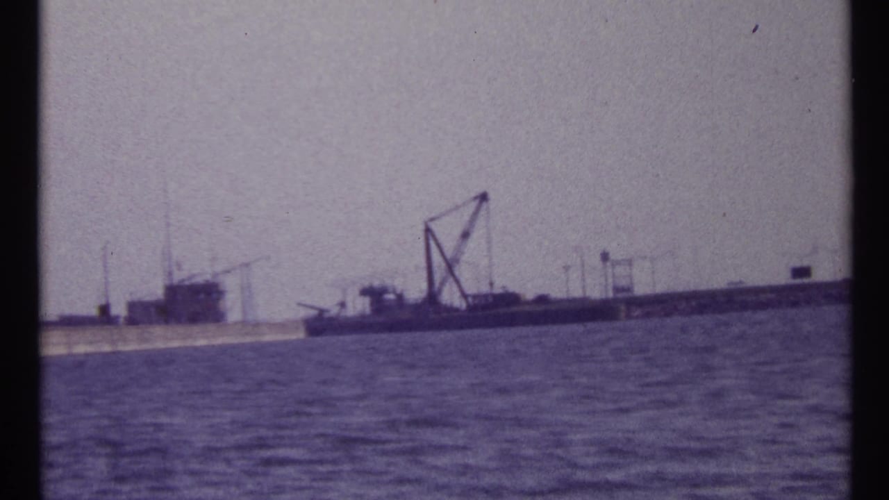 Waterfront barge and crane seen across rippled water.