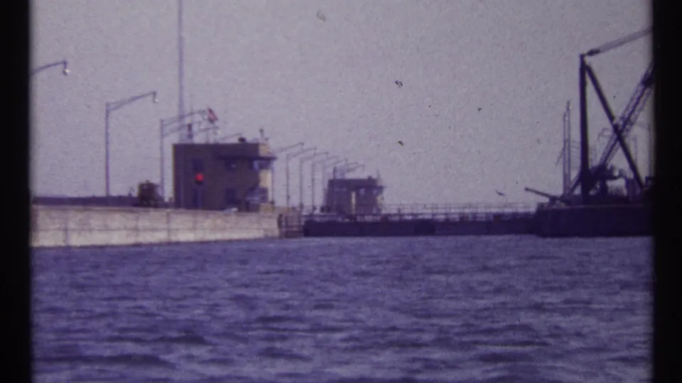 1967 Montreal 8mm frame showing river water, lock walls, control buildings, lights, and a large crane at the right edge.