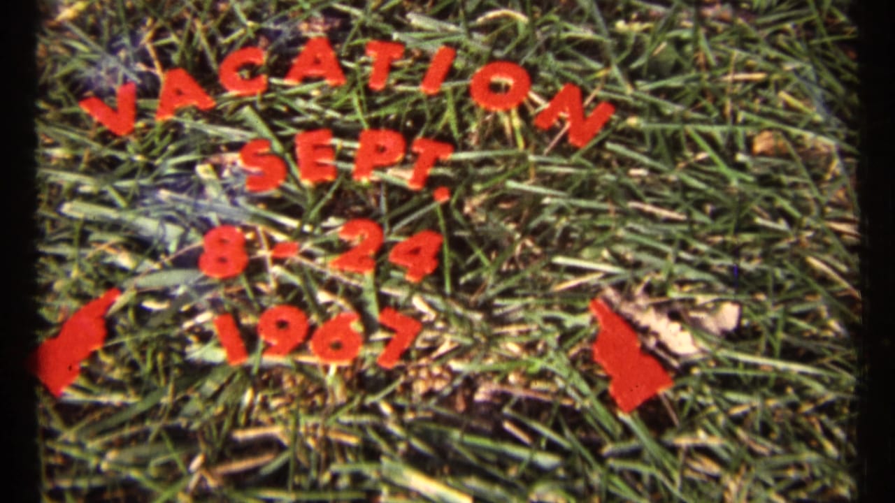 Red cutout vacation dates arranged on grass.