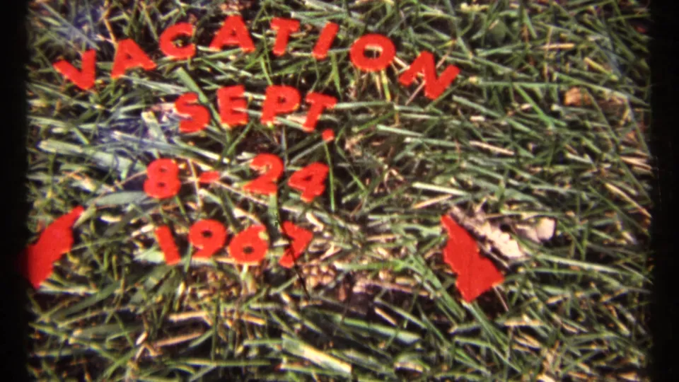 The handmade 1967 vacation title card fills the frame, showing red cutout text across the lawn.