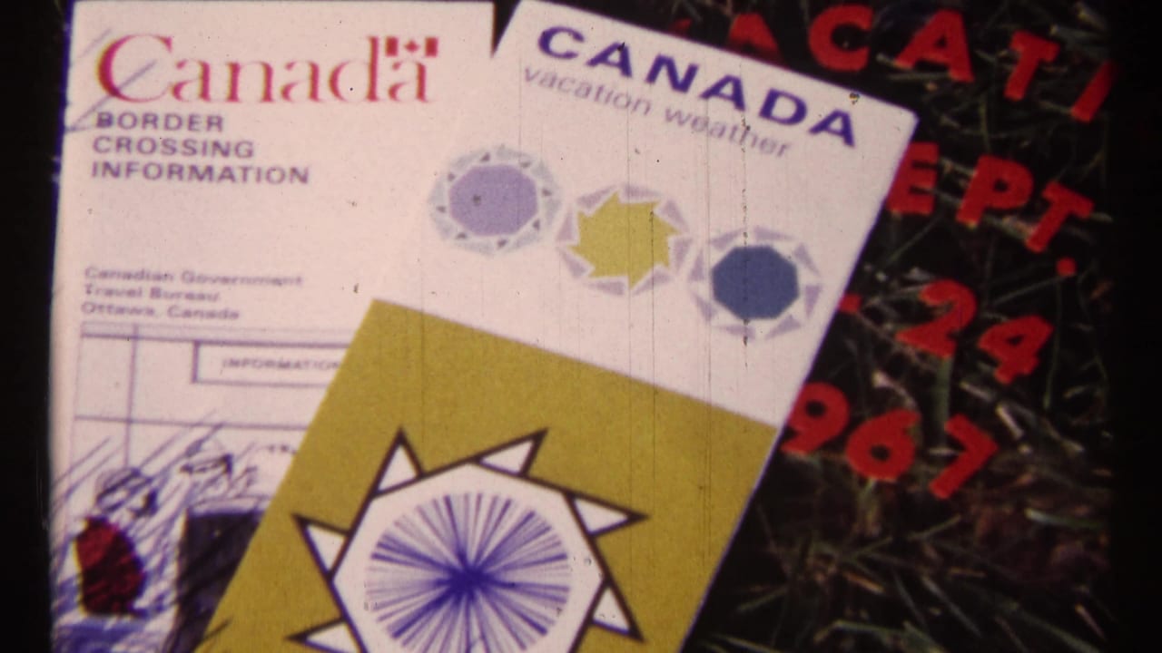 Canada travel brochures and border crossing information lying on grass beside red date lettering.