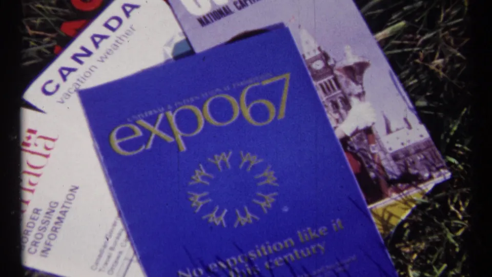 1967 home-movie still showing a blue Expo 67 booklet placed over Canada and Ottawa travel brochures outdoors.