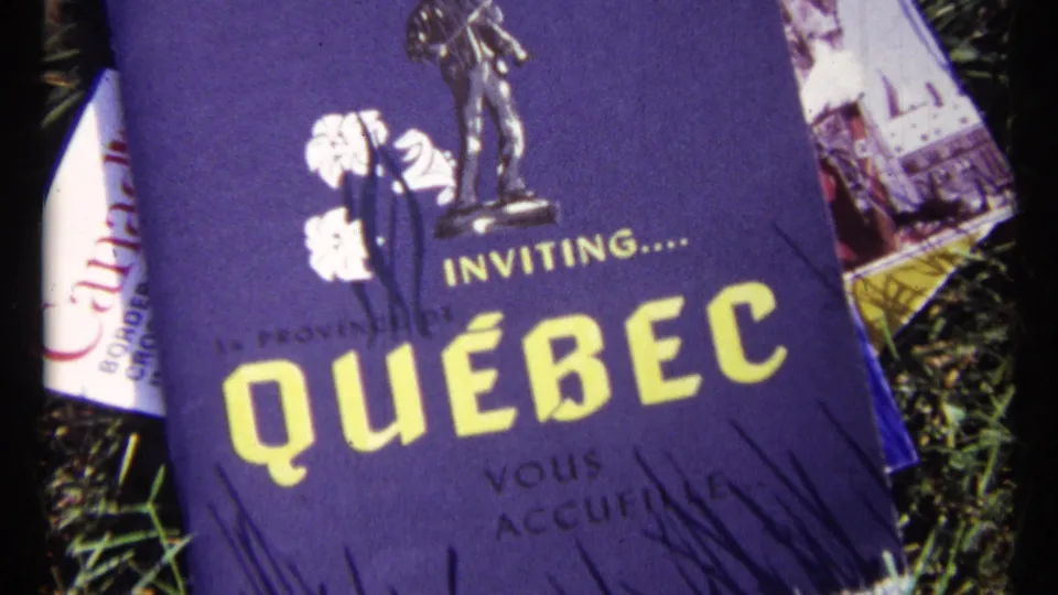 Close 8mm view of a Quebec travel brochure in 1967 Ottawa footage, with Canada paperwork partly visible behind it.