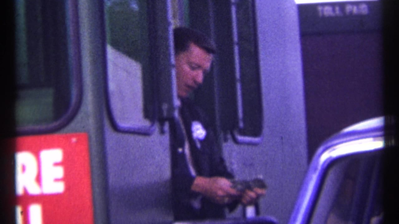 Officer looks down while counting cash at the toll booth beside the car window.