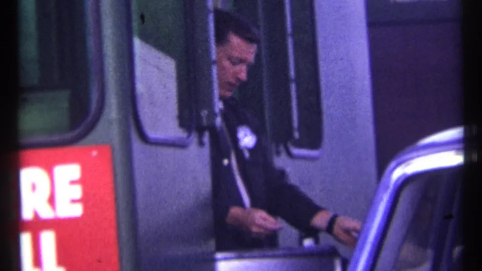 The officer reaches toward the car at the toll booth during a brief cash exchange in 1967 Ottawa footage.