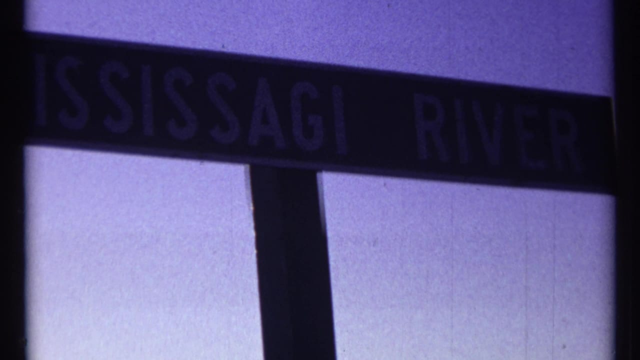 Dark sign reading MISSISSAGI RIVER against a pale purple sky.