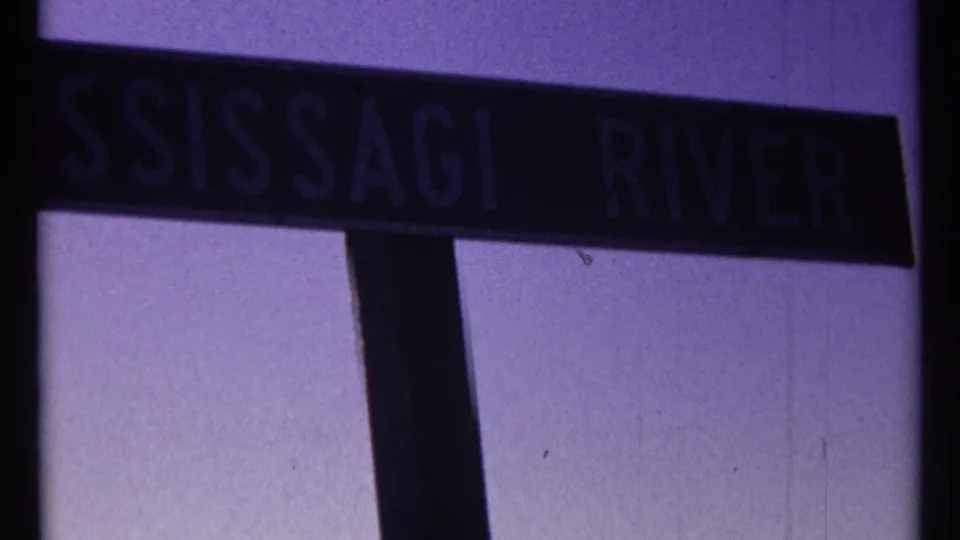 Final 1967 home-movie frame shows the MISSISSAGI RIVER sign at an angle against the sky.