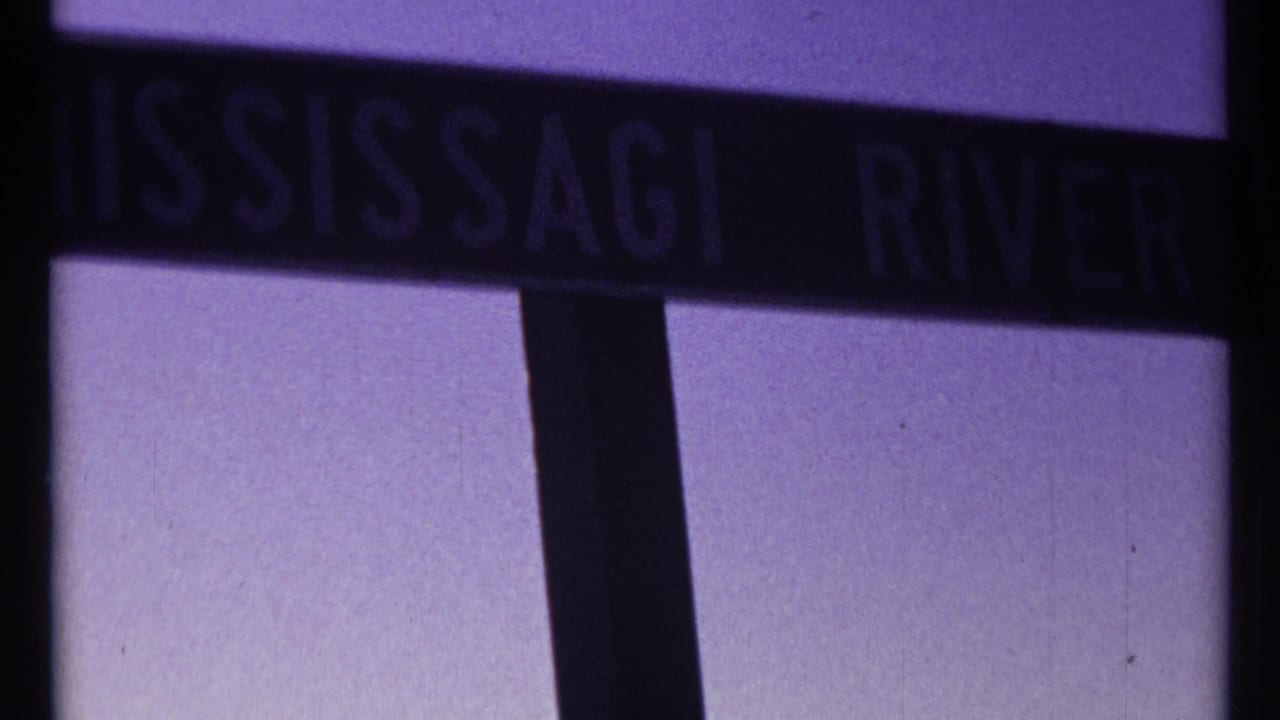 Dark Mississauga River sign seen close up with purple-tinted film color.