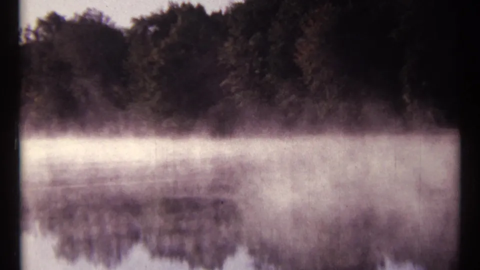 Misty Mississauga River view near Ottawa, with low fog over calm water and a dark tree line reflected in the surface.