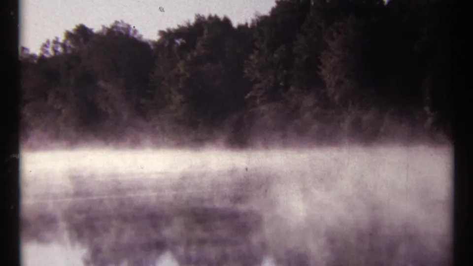 1967 8mm river scene near Ottawa, showing pale fog suspended above still water and dense trees along the far shore.