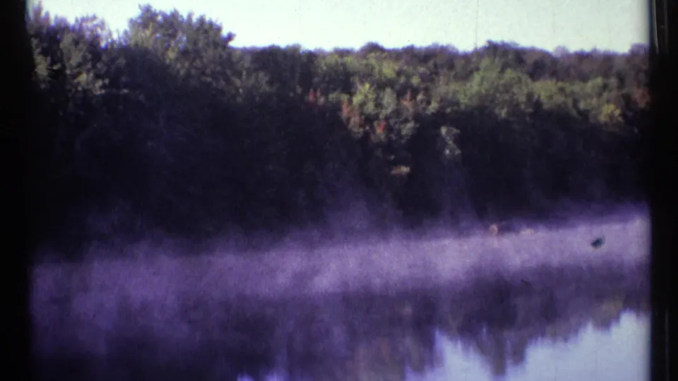 Color-shifted 8mm view of the Mississauga River near Ottawa, with trees, purple-tinted mist, and mirrored water reflections.