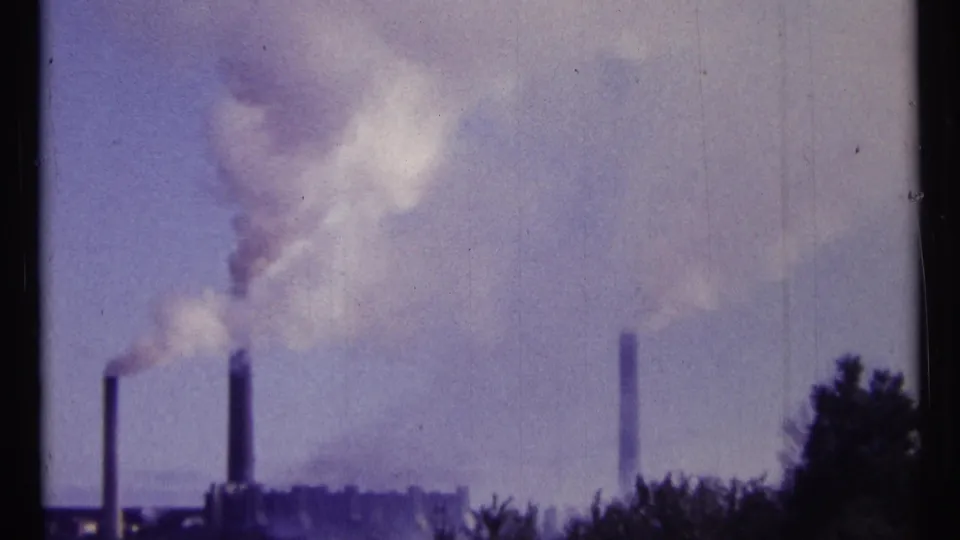 1967 Ottawa 8mm frame of three industrial smokestacks emitting smoke beneath a hazy blue-purple sky.