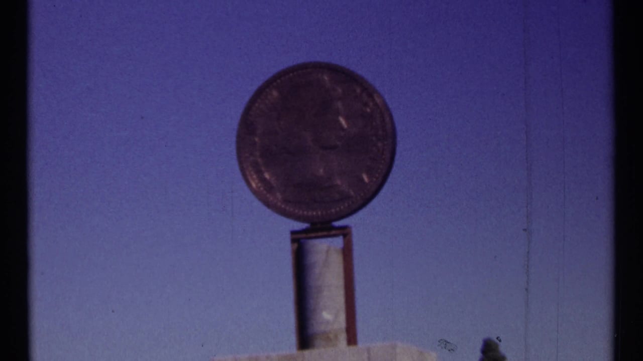 1967 Ottawa 8mm frame showing a round coin-like monument on a narrow support, with the image softened by exposure and focus.