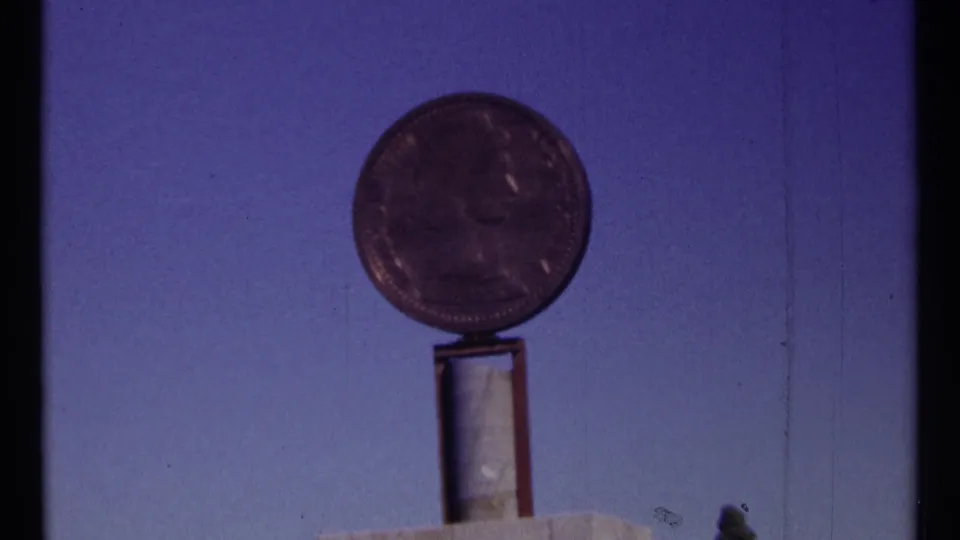 1967 Ottawa 8mm frame showing a round coin-like monument on a narrow support, with the image softened by exposure and focus.