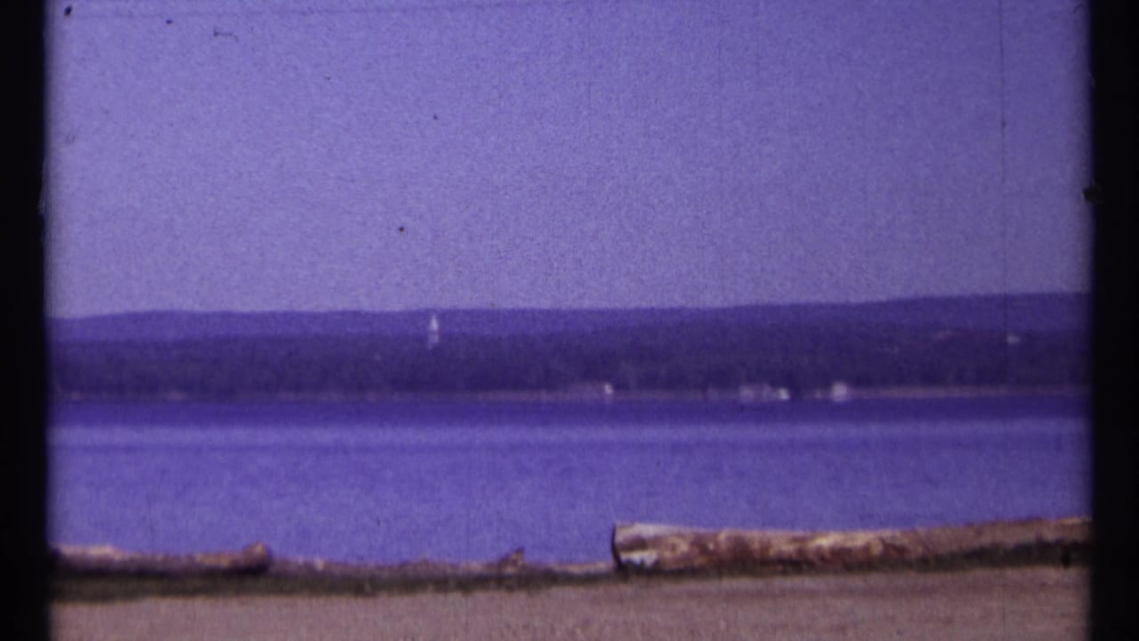 Calm water with a distant shoreline under a clear sky.
