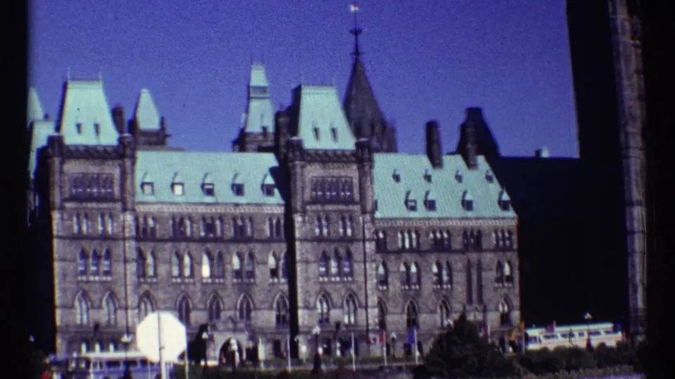 Ottawa Parliament Buildings exterior in 1967, showing Gothic Revival stonework, pale roofs, and small figures near the entrance area.