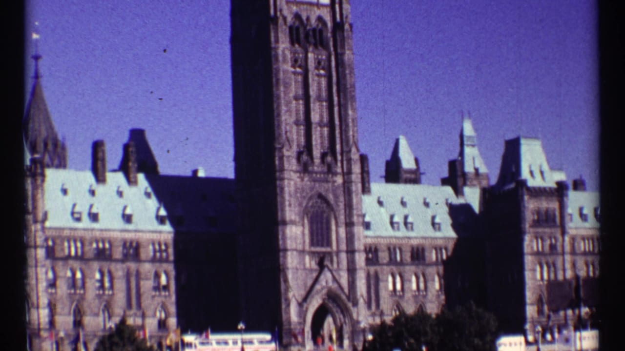Peace Tower and Parliament buildings under a blue sky, seen on vintage 8mm film.